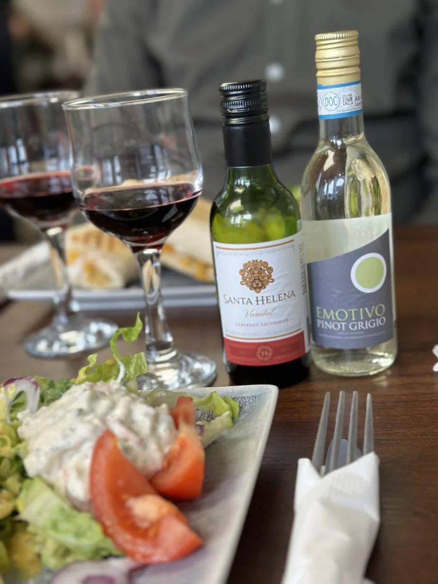 Small bottles of red and white wine with two glasses of red